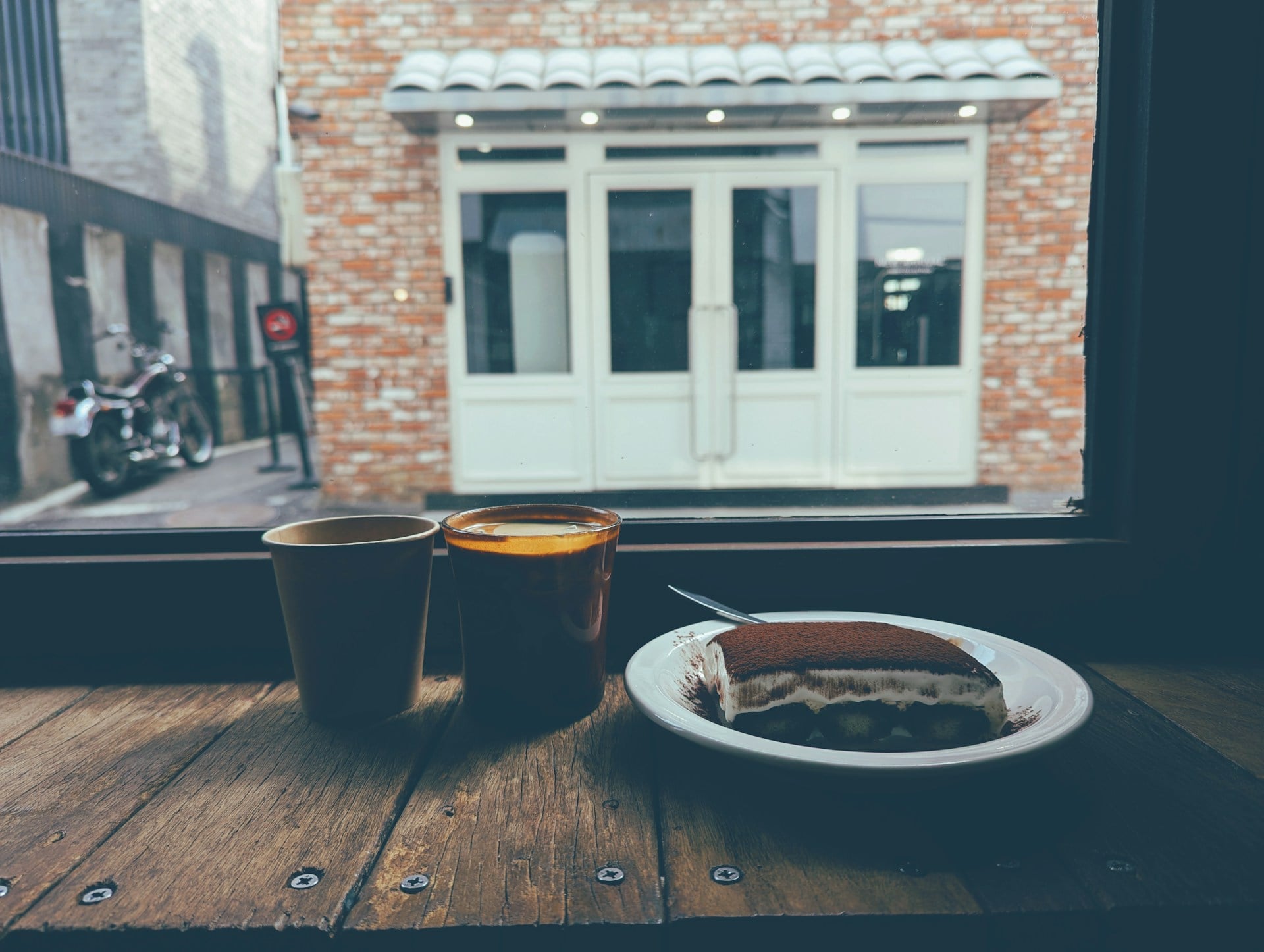 Kaffekopper og kage ved et cafévindue