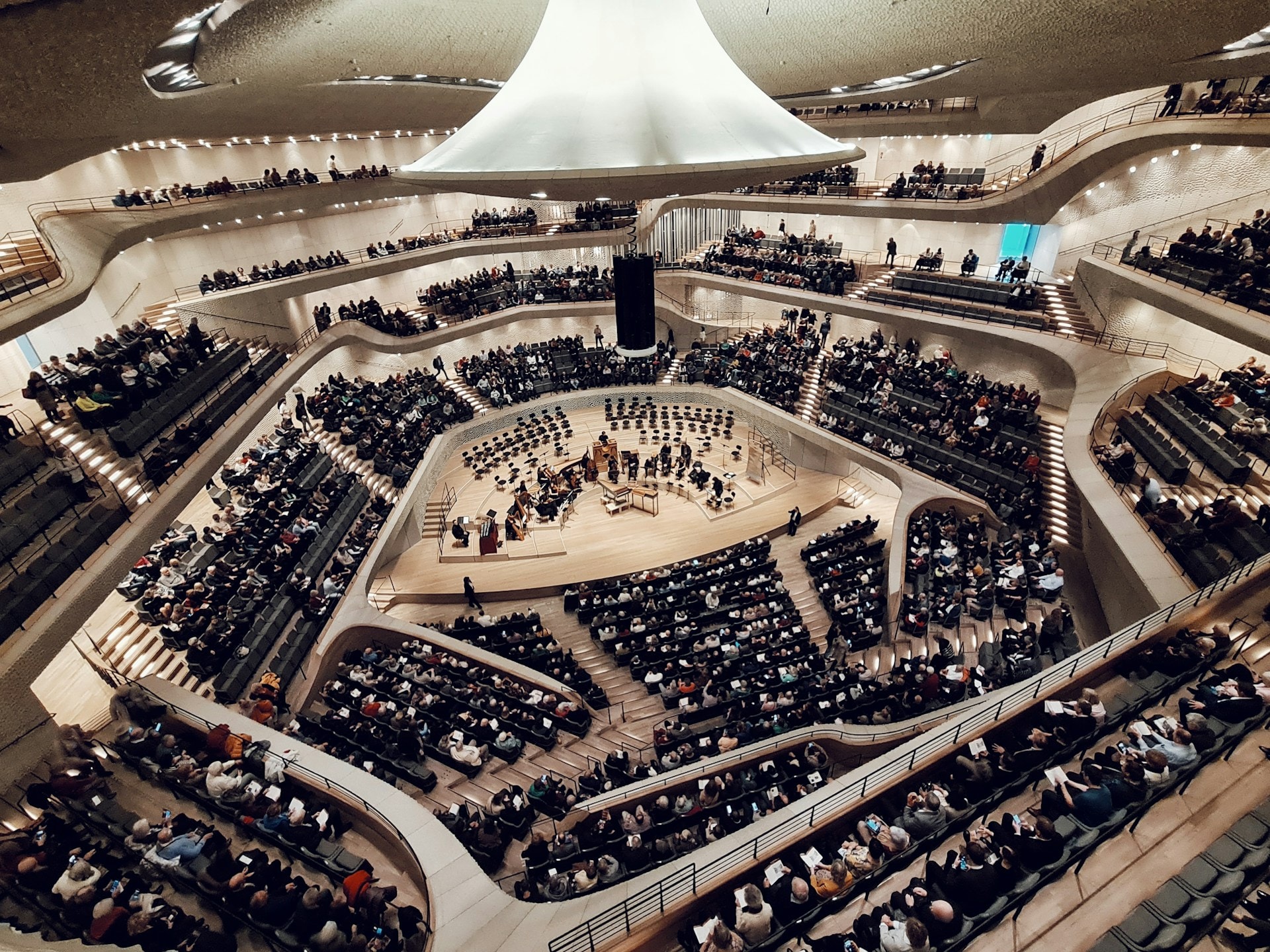 Et koncerthus set fra publikum med et orkester og kor på scenen under buede lofter
