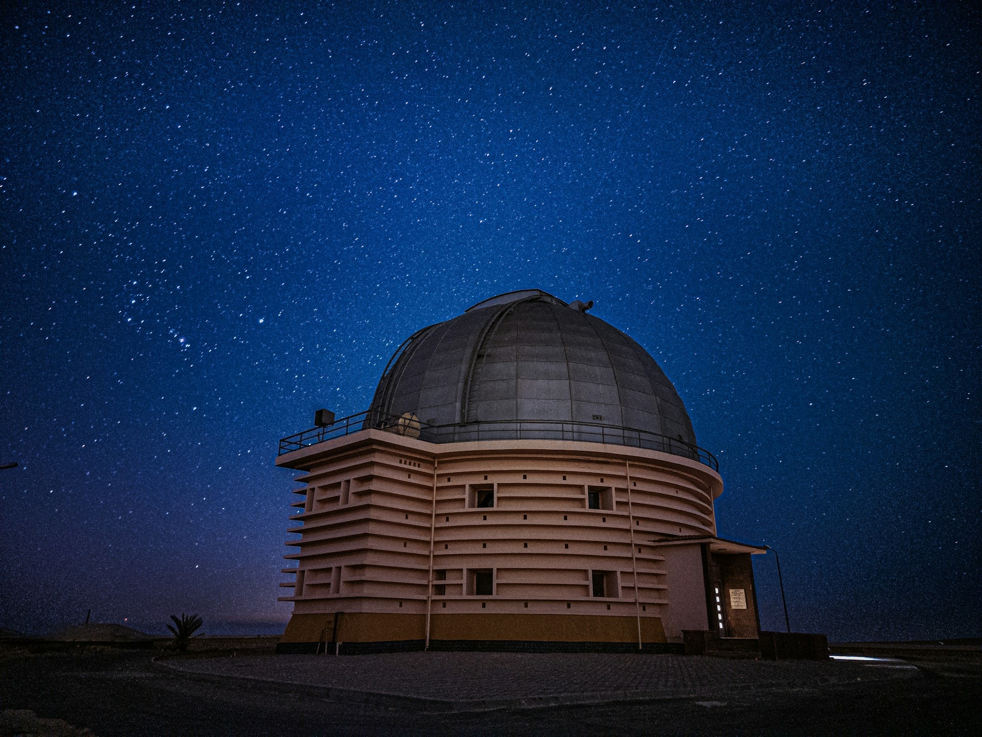 Et hvidt observatoriedomes silhuet under en klar, stjernefyldt nattehimmel