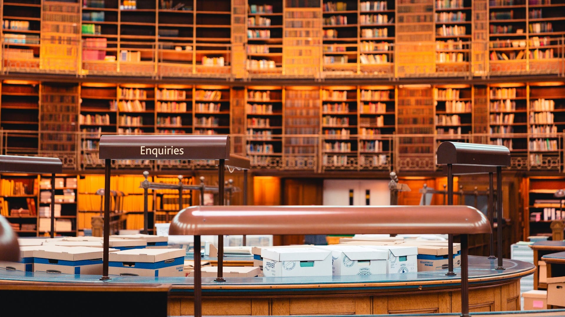 Et stort offentligt biblioteks læsesal med bogreoler hele vejen rundt og en skranke til forespørgsler